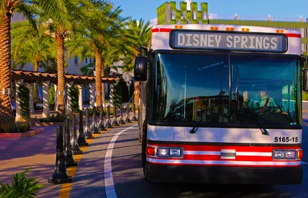 Disney volta a exigir reservas para embarque nos ônibus de Disney Springs para hotéis. Veja quem poderá utilizar o transporte. Ônibus da Disney em Disney Springs realizando transporte para hotéis Disney
